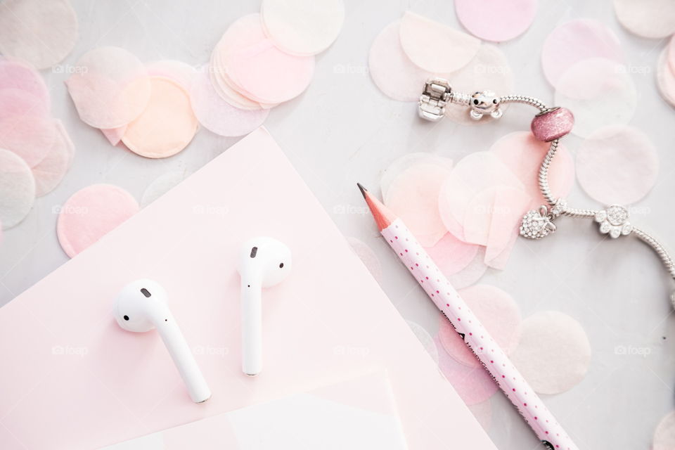 Flatlay items: wireless headphones, notebook, pencil, bracelet , confetti lying on gray concrete background 