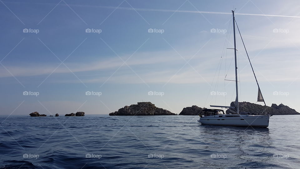 boat on calm peaceful ocean water with rocky land and blue sky in Croatia