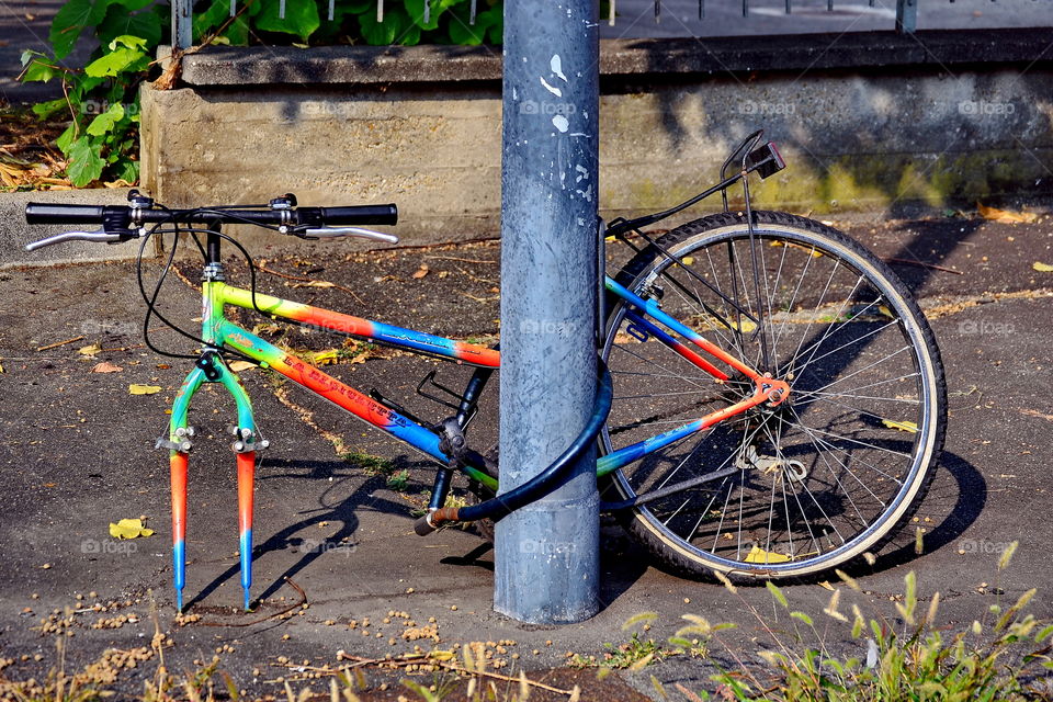 a bicycle tied to a pole, a wheel was stolen