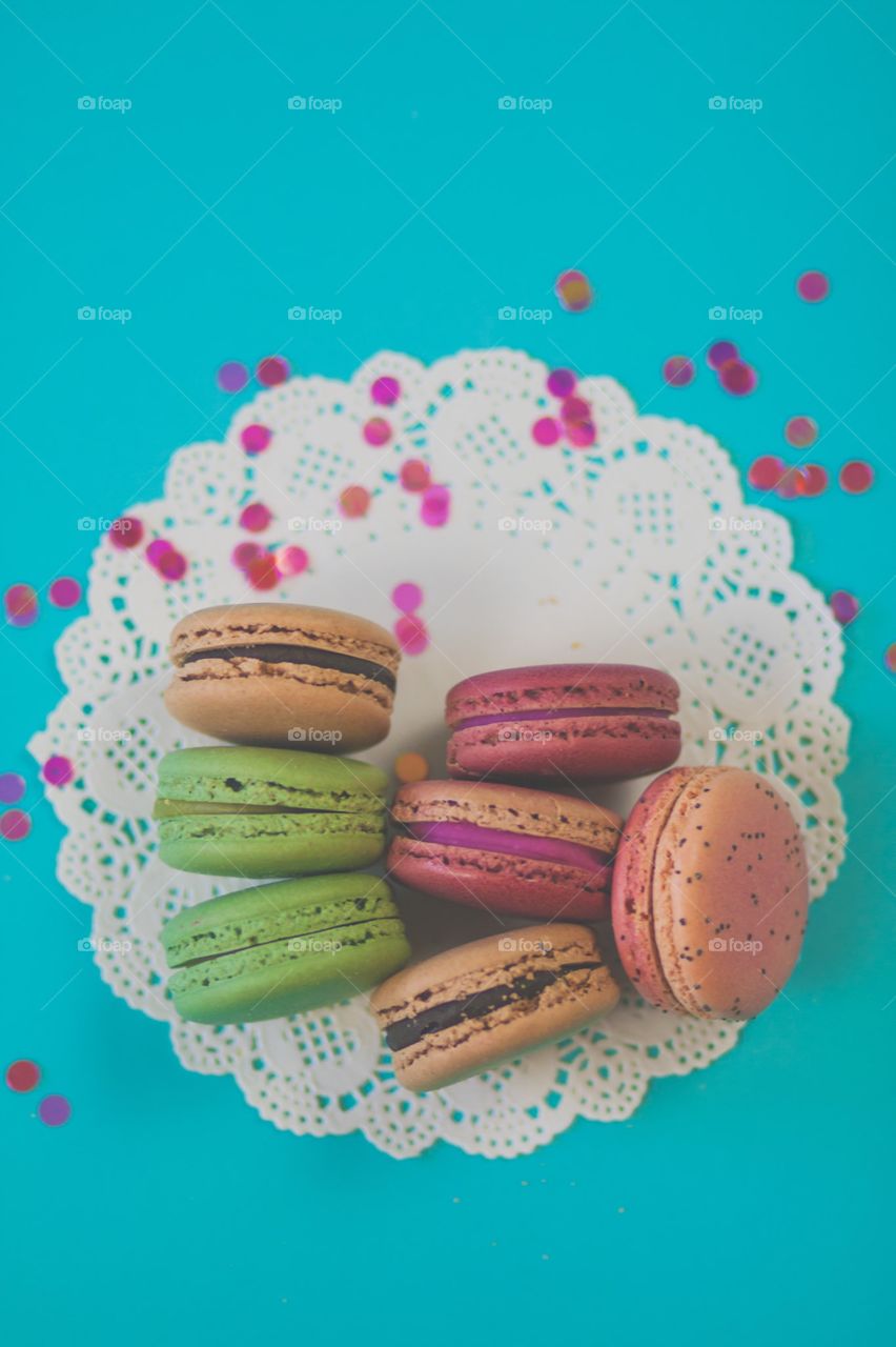 French Macarons. Colorful French Macarons on a white paper doily, against a turquoise blue background.
