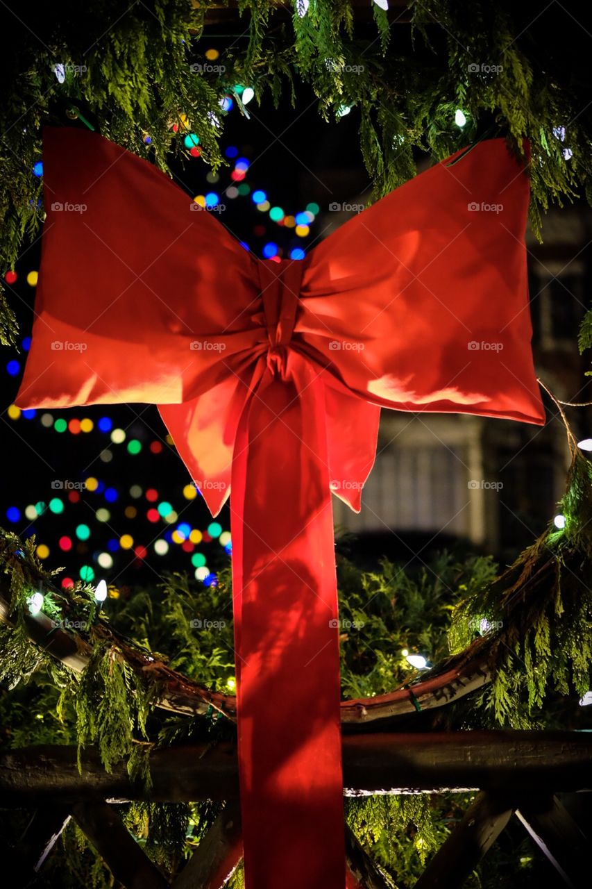 Red Bow Christmas Wreath With Blurred Lights In The Background 