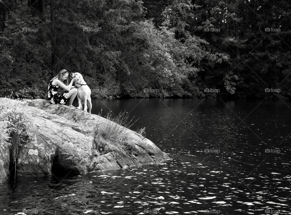 Girl with her white dog on rock outcropping 