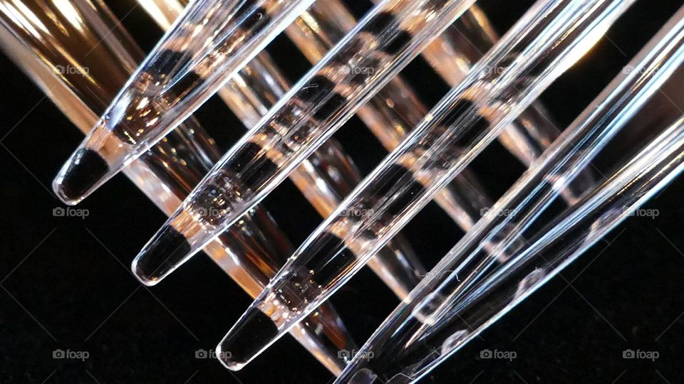 Closeup of two diagonal overlapping clear plastic forks against black background 