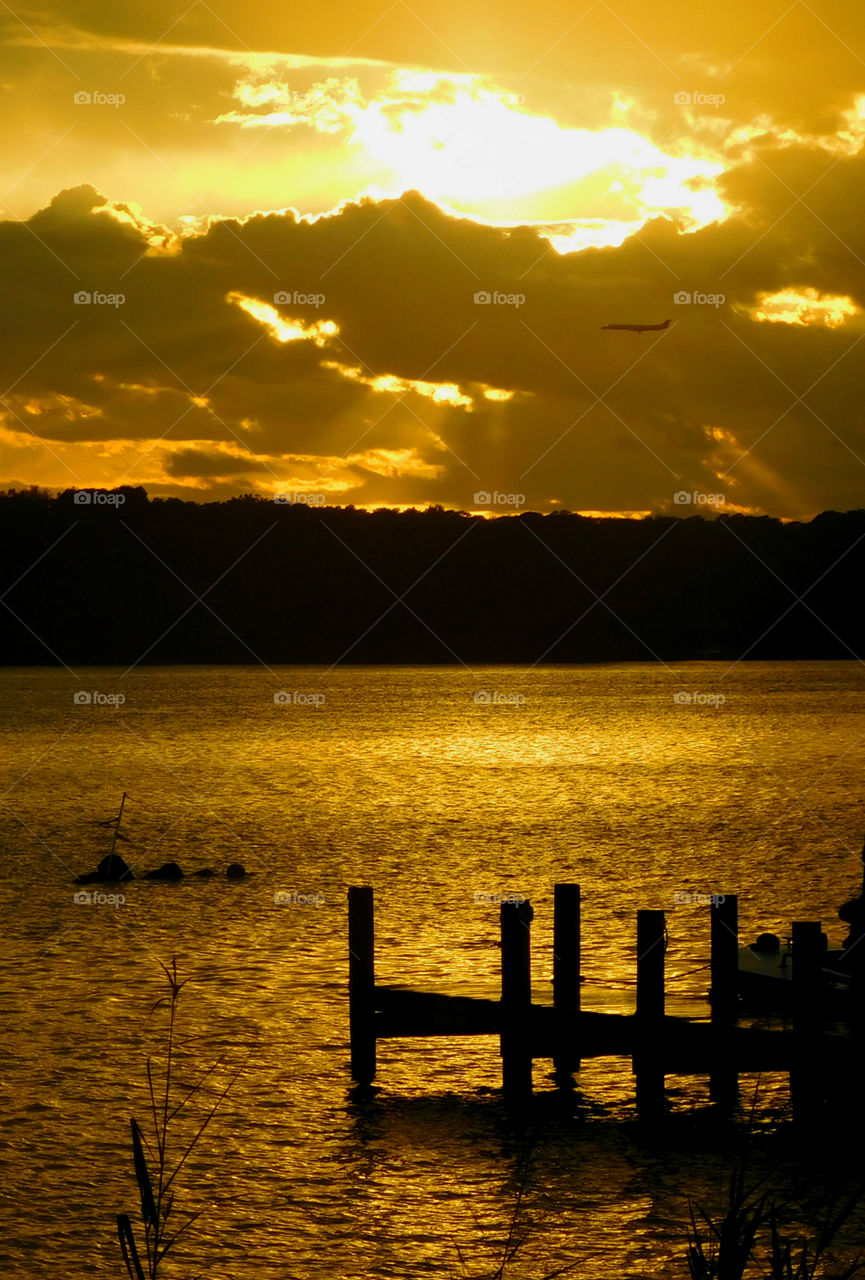 Airplane flying over lake at sunset