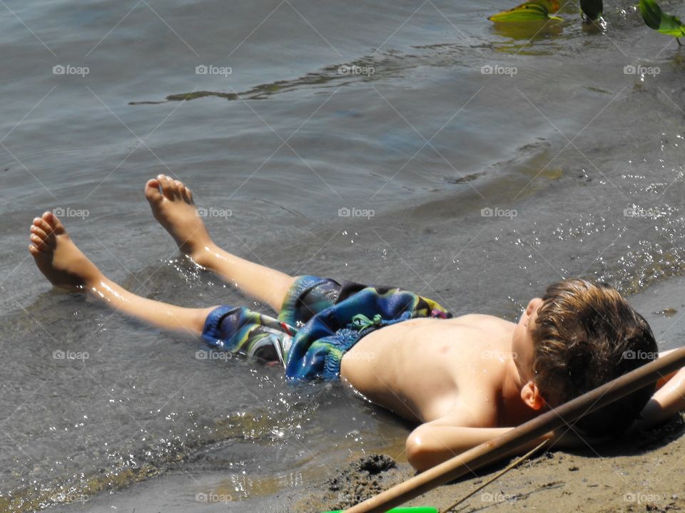 Young boy sunbathing on the beach
