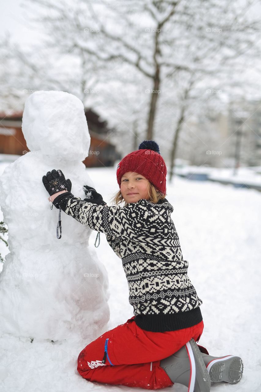 Amazing winter time, happy boy makes a snowman