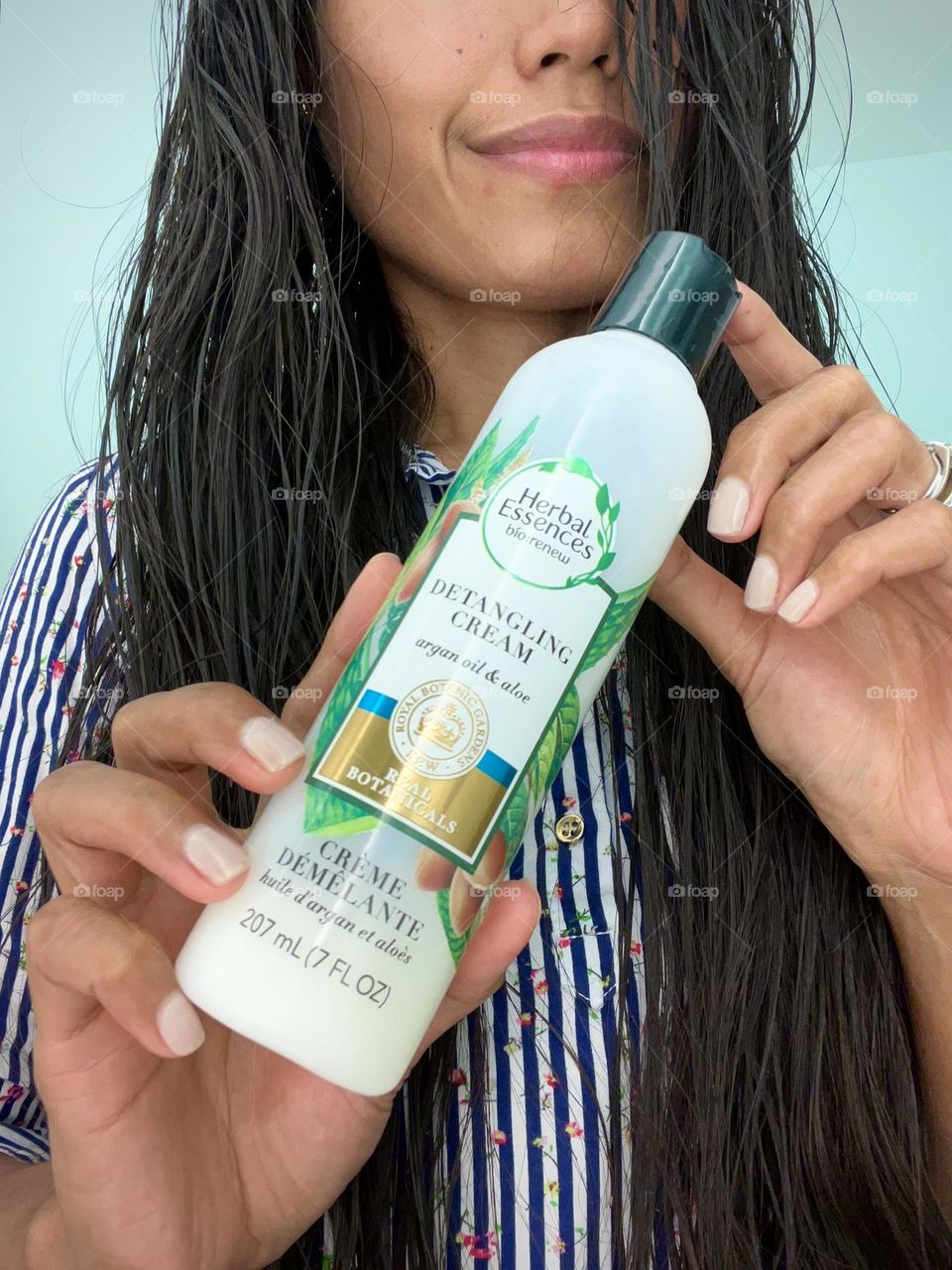  A woman holding a Herbal essences detangling cream