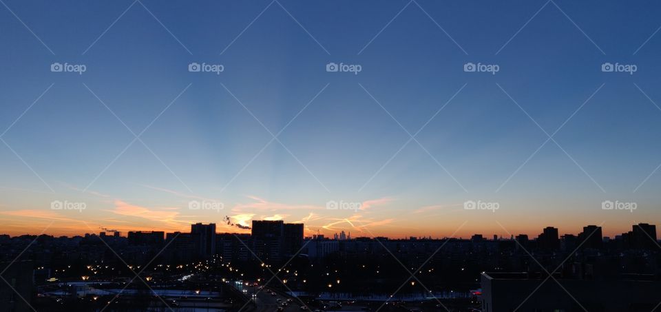 rays of the sun at sunset on the background of the cityscape