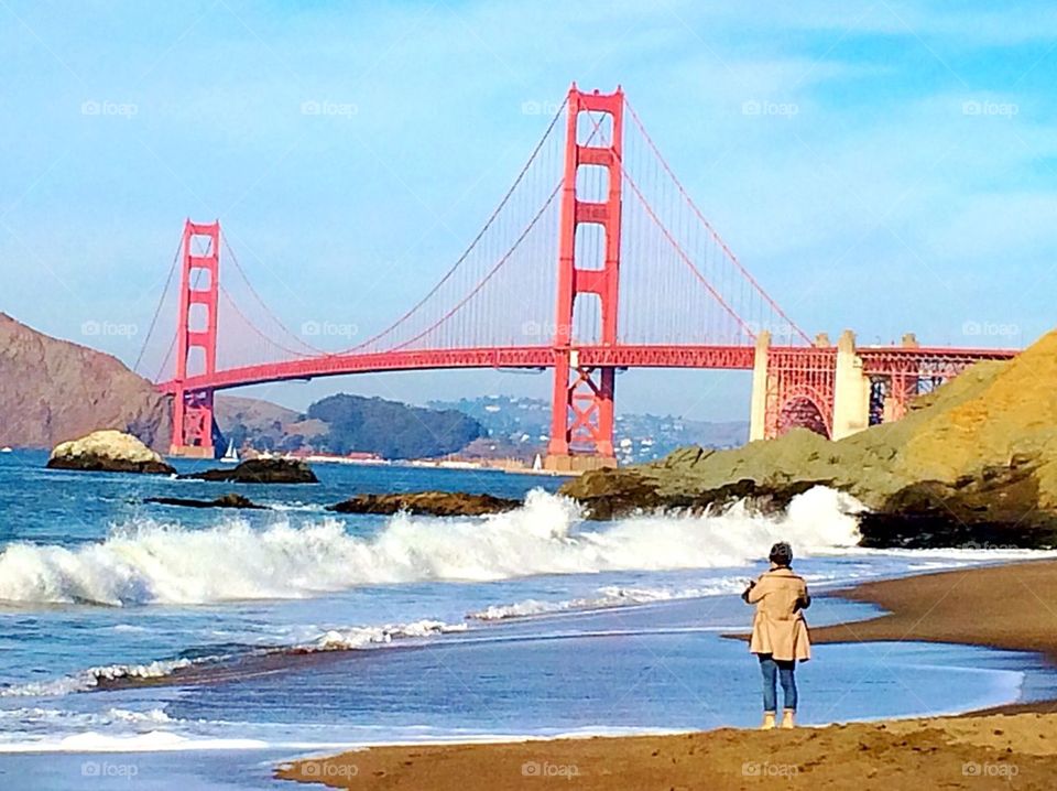 Golden Gate Bridge with lady watching with splashing waves