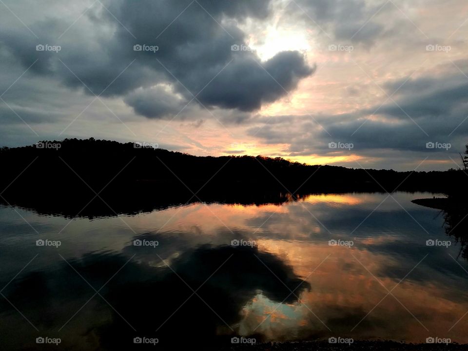 storm clouds reflecting on lake during sundown.