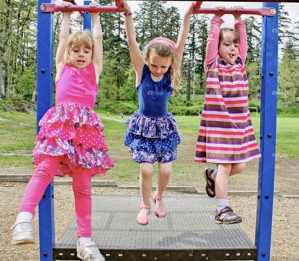 Three friends hanging from monkey bars