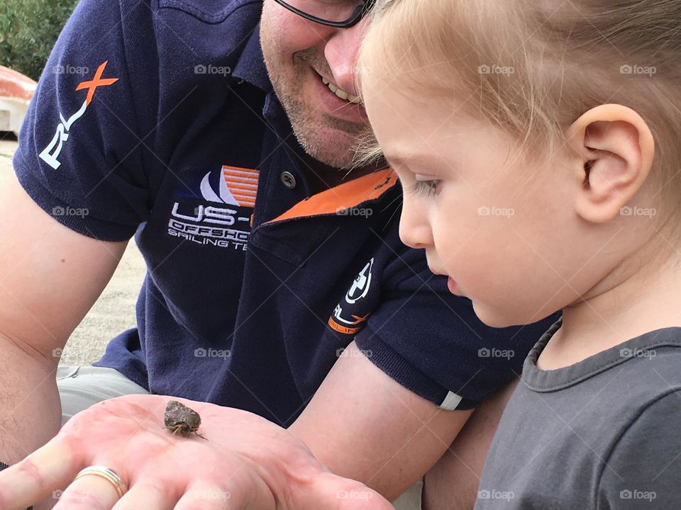 A father showing his daughter the wonders of a sea creature.