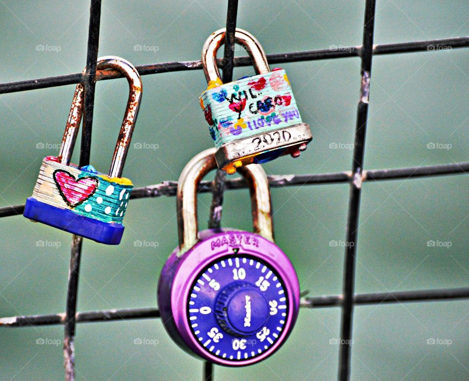 3 love locks locked to a fence on a pier on a cold Misty day