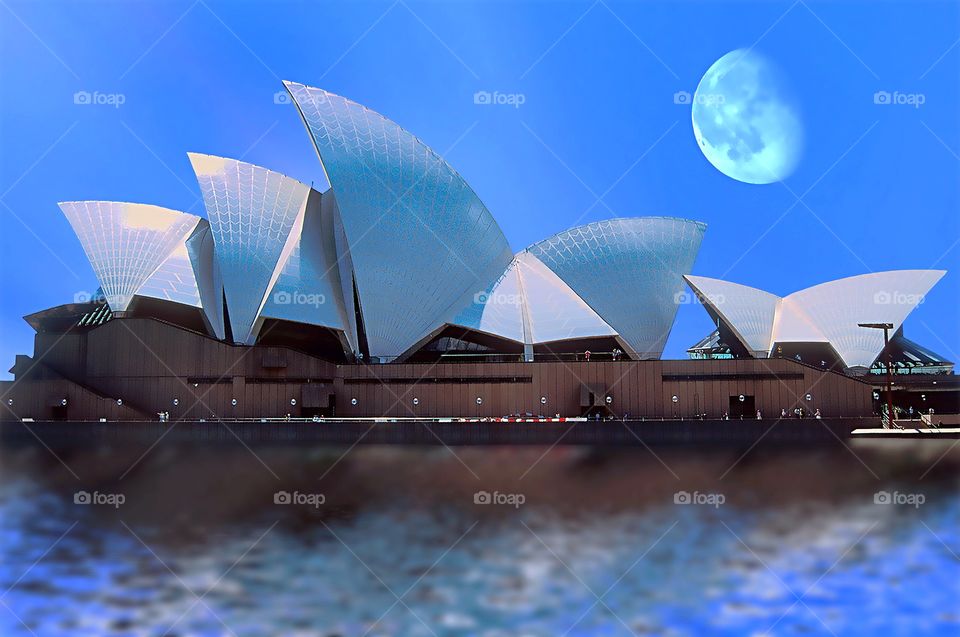 An early evening moon rises over Sydney Opera House.