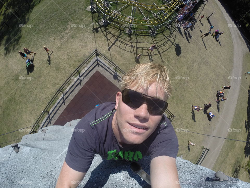 Young man climbing a wall at a theme park Tomelilla sommarland in Swedenz