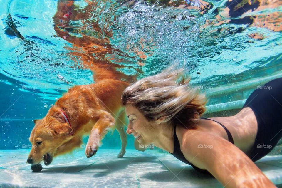 Woman with her dog swimming underwater
