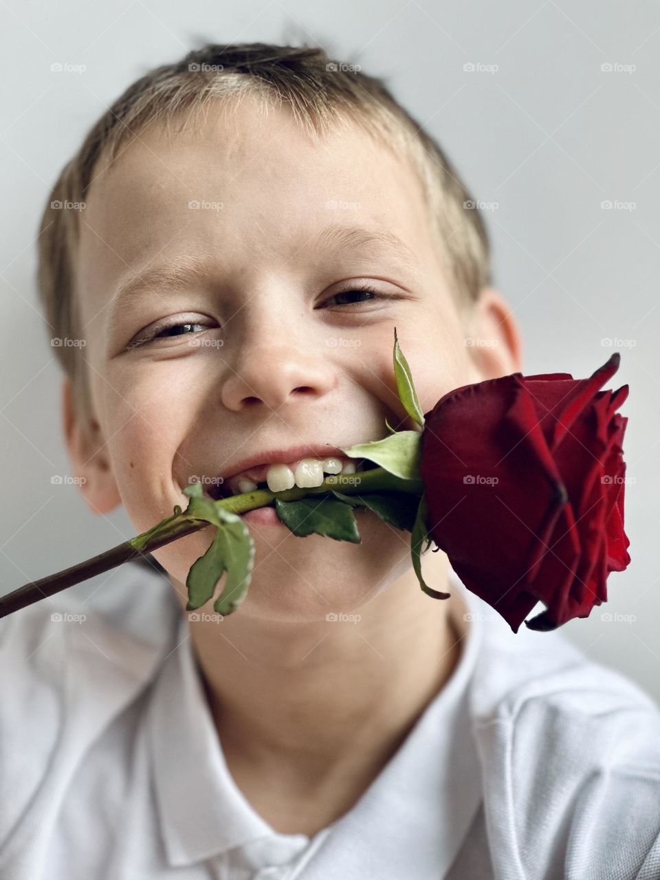 smiling boy with a rose in his mouth