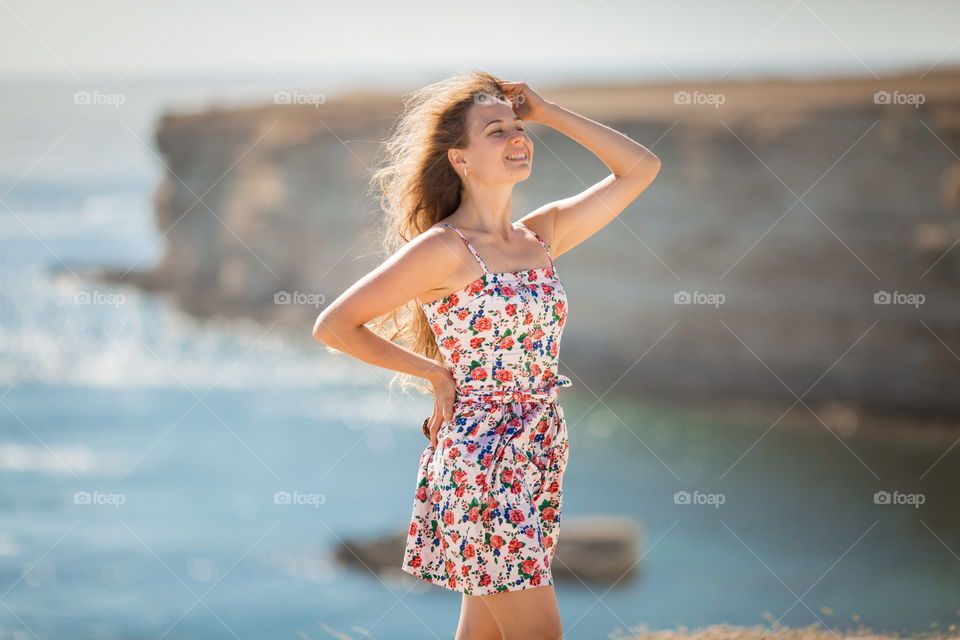 Portrait of beautiful young woman near the sea at sunset