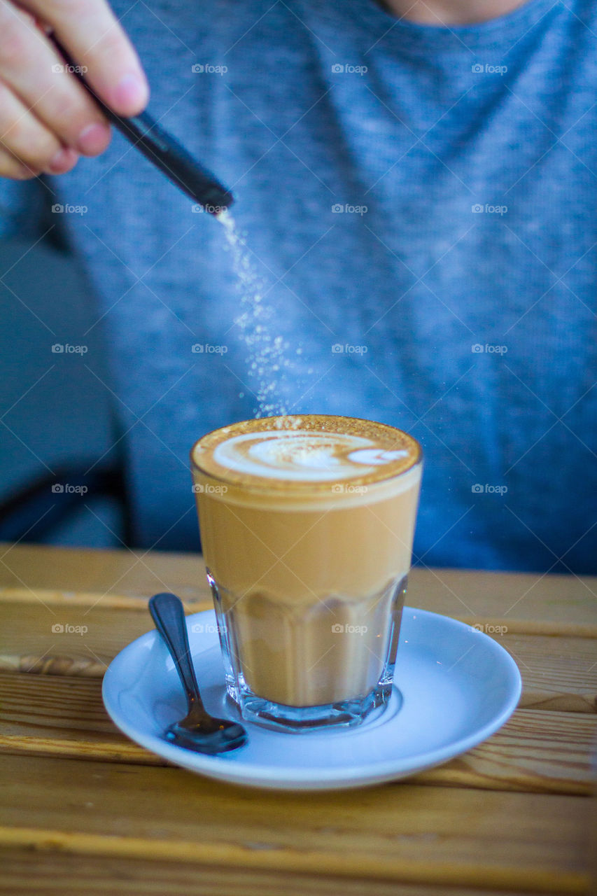 My favourite form of liquid - freshly brewed cappuccino! Image of person adding sugar to cup of coffee.