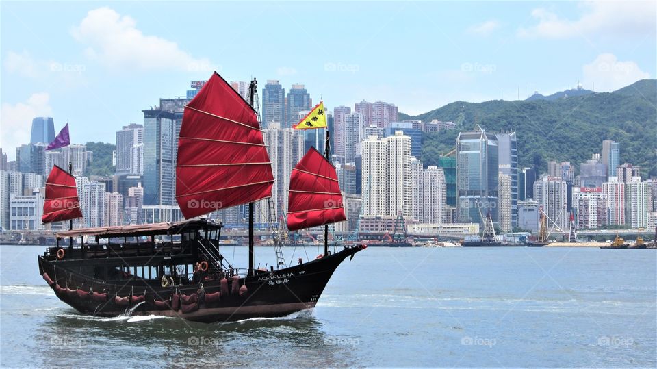 A traditional Chinese junk boat moves through the waters near Hong Kong on a clear day.