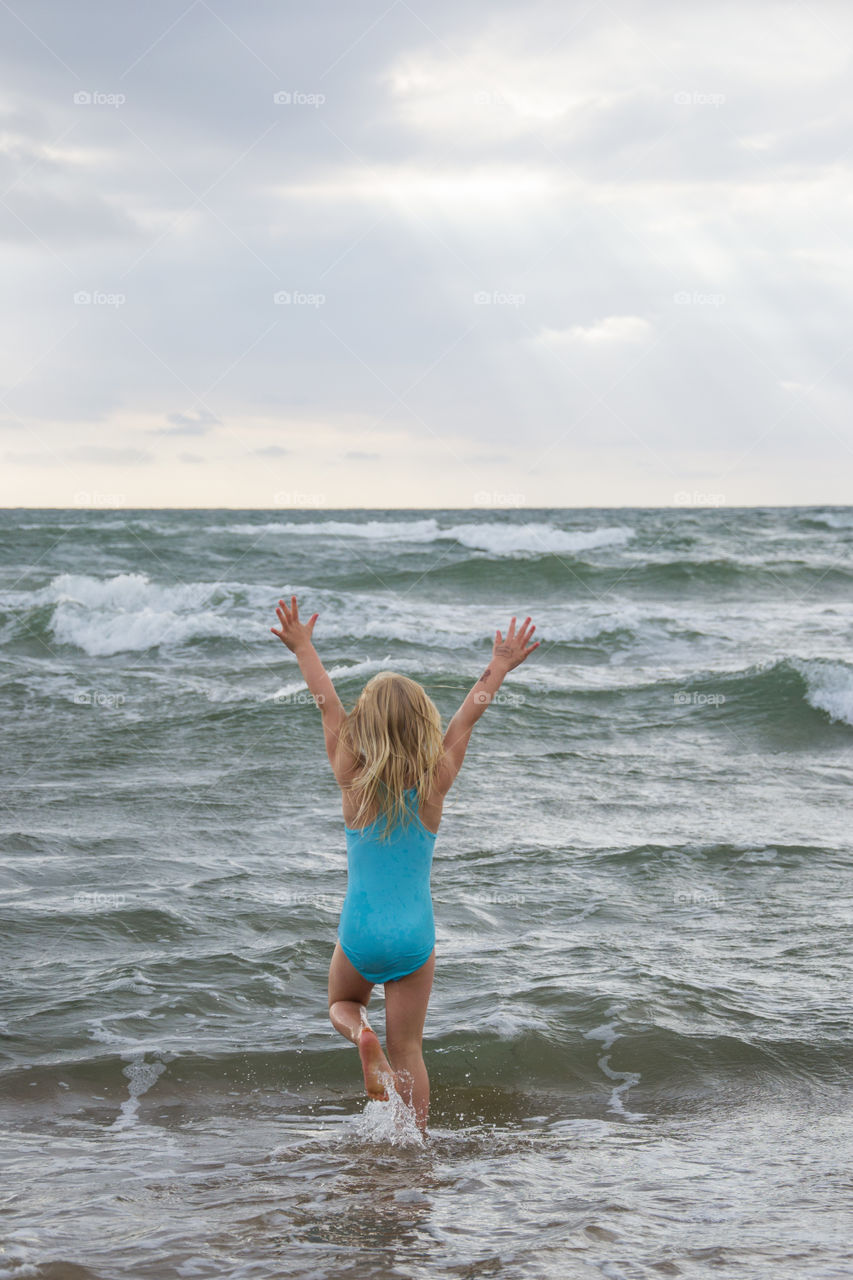 Girl playing at the beach of Tylösand outside Halmstad in Sweden. It's about to get stormy weather but the girl is having fun swimming and playing in the water.