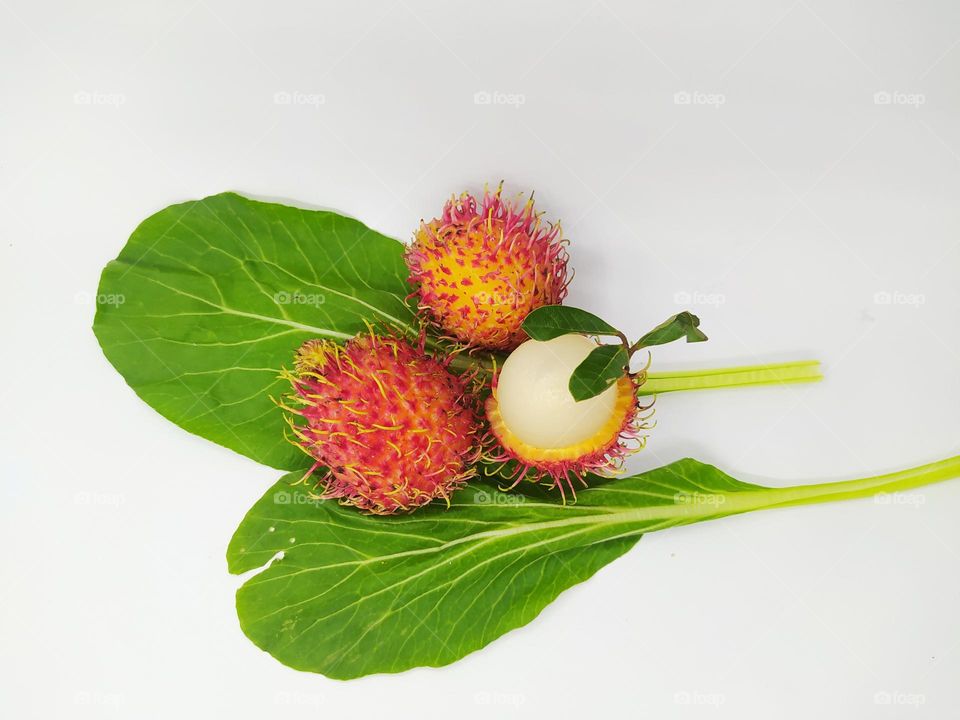 Rambutan fruit and green mustard leaves isolated on white background, fruit and vegetable