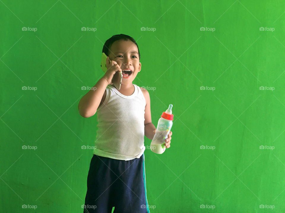 A happy little boy talking with someone on the phone