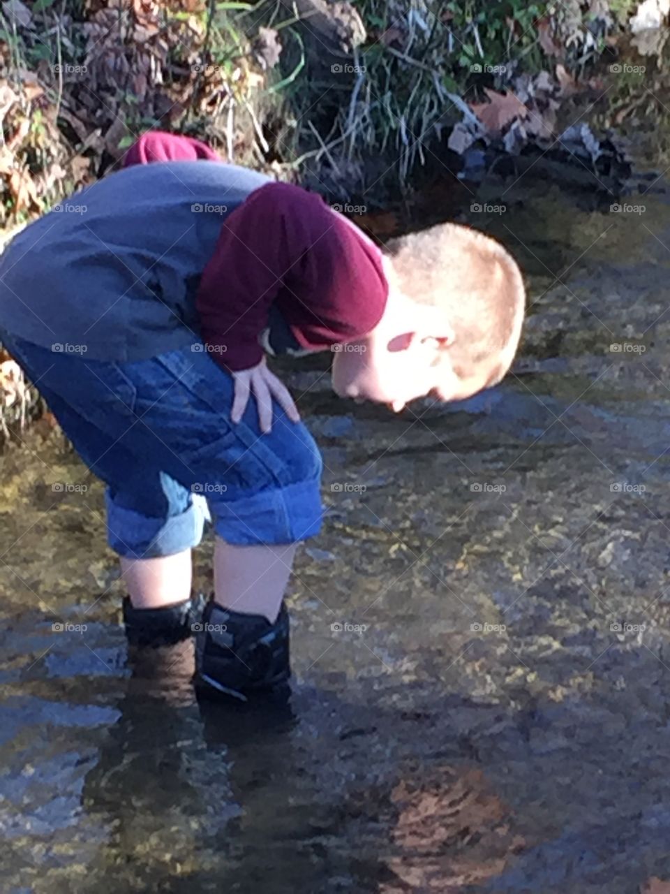 Young boy exploring stream. 