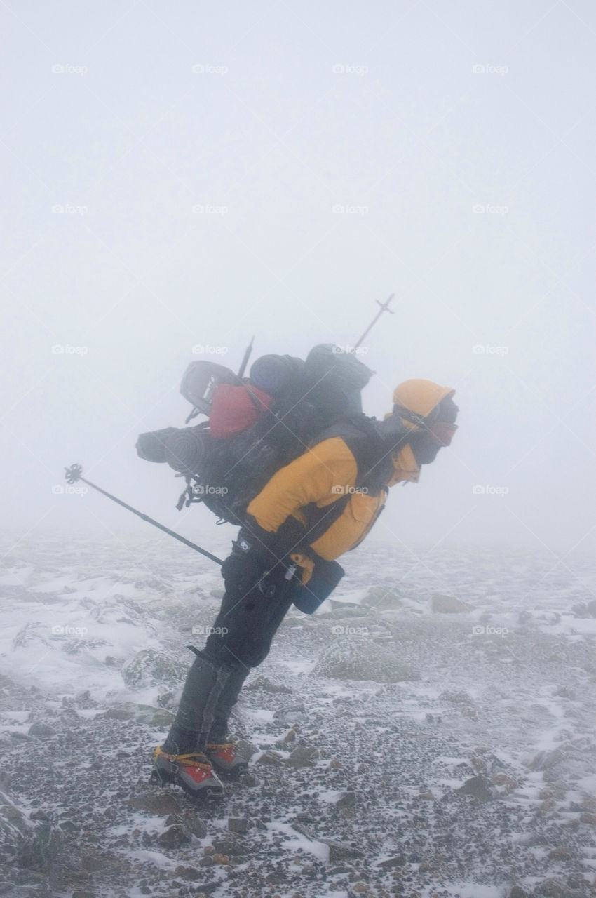 Backpacker leaning into the wind on the summits of the presidential