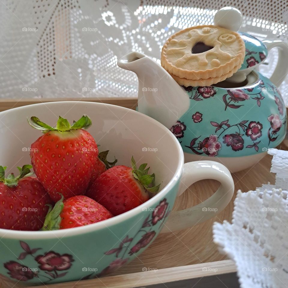 teapot for tea drink. English. strawberries in a teacup on a tray in natural light
