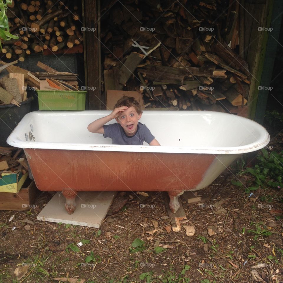 Six year old boy playing in a old bath. Six year old boy playing in a old cast iron roll top bath