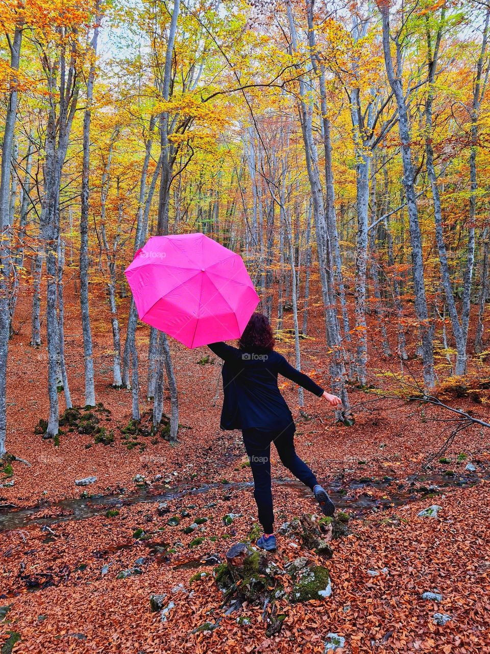 woman from behind in the woods with open pink umbrella