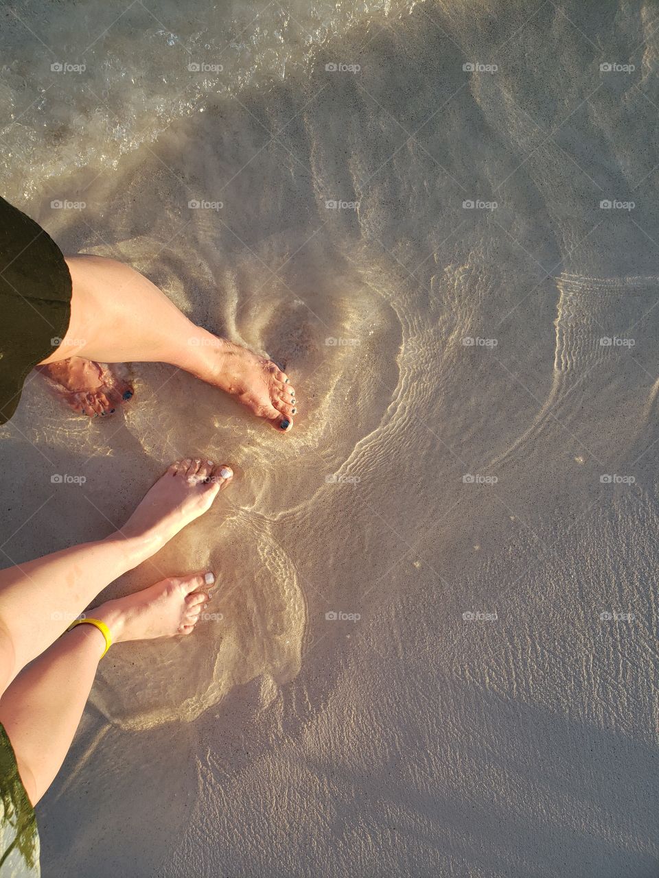 Mother and Daughter feet and toes in sand with ocean tide on sunny beach vacation