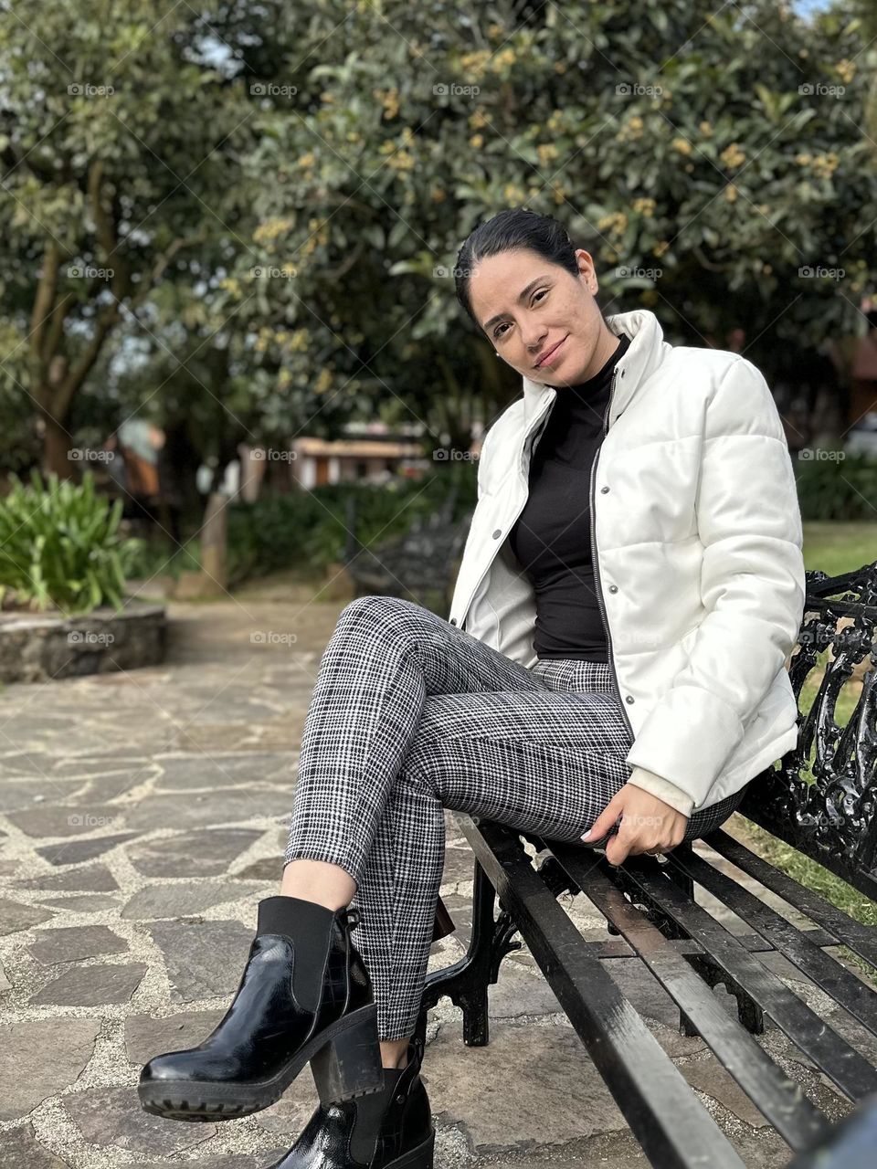 Portrait of woman smiling while she sitting on a chair in the park.