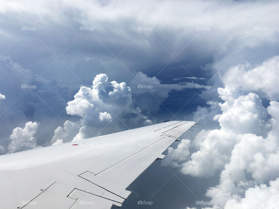 Airplane wing flying around storm clouds