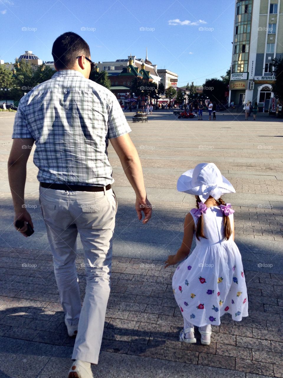 dad walks with the little daughter through the streets of the city