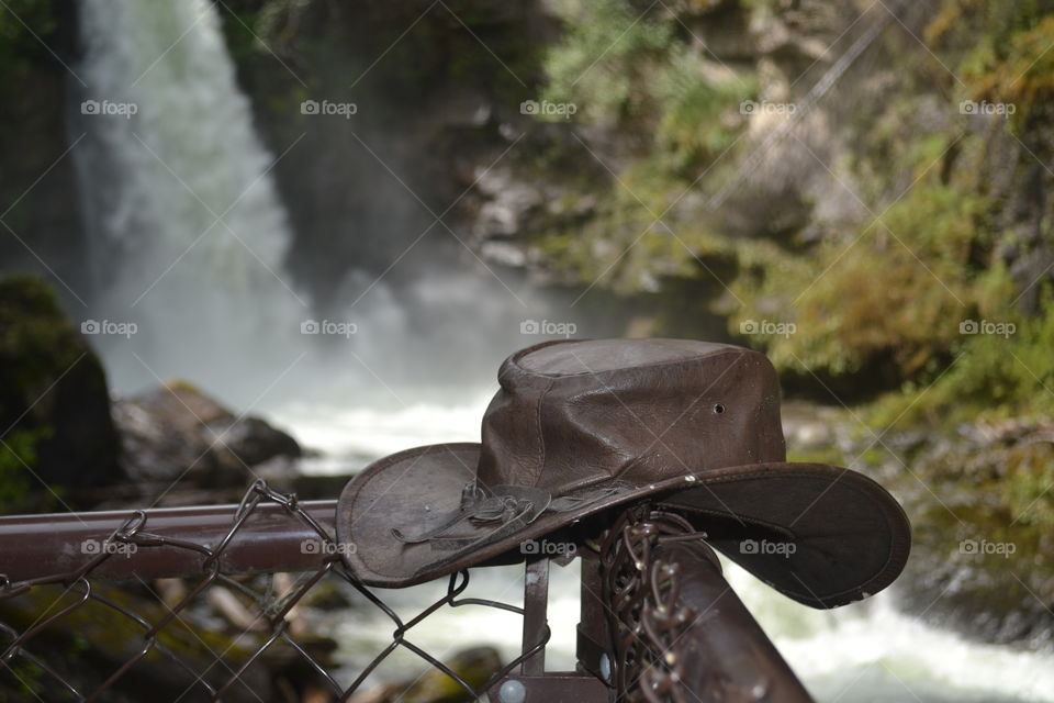 Australian leather bush cap hanging on post in front of waterfall in Canadian Rocky Mountains at Banff national park 
