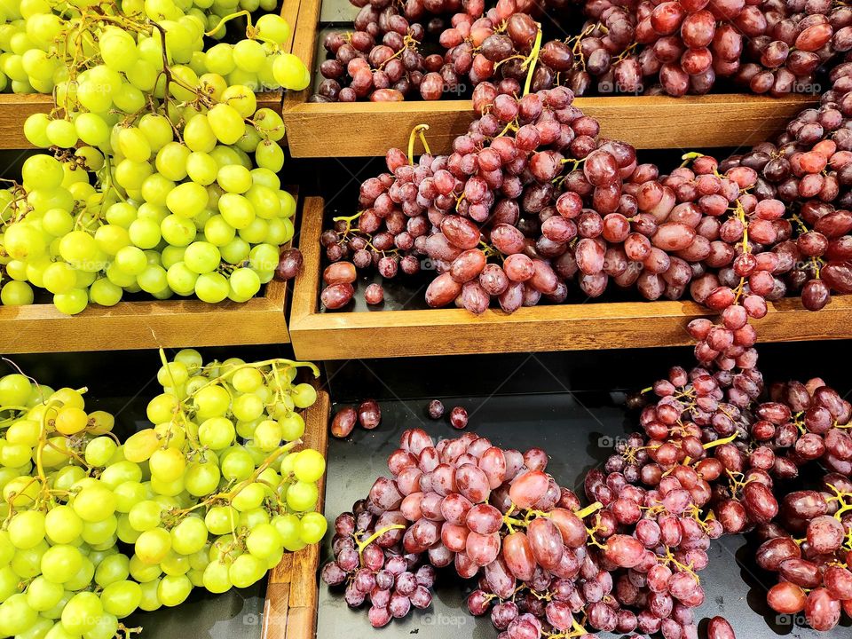 enticing fresh bright green and red grapes for sale on wooden shelf levels in an Oregon market