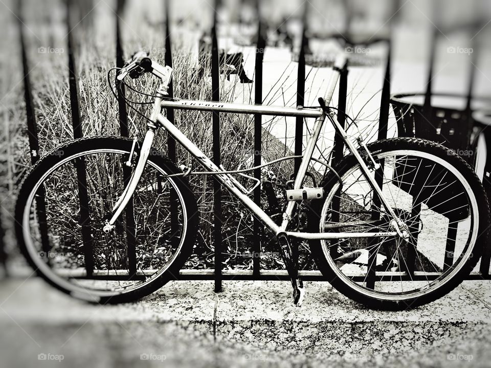 Black and white photo of bicycle chained to gate near World Trade Center in New York City.
