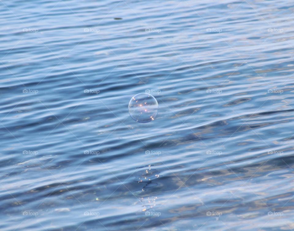 Shiny soap bubble floating over the open sea.