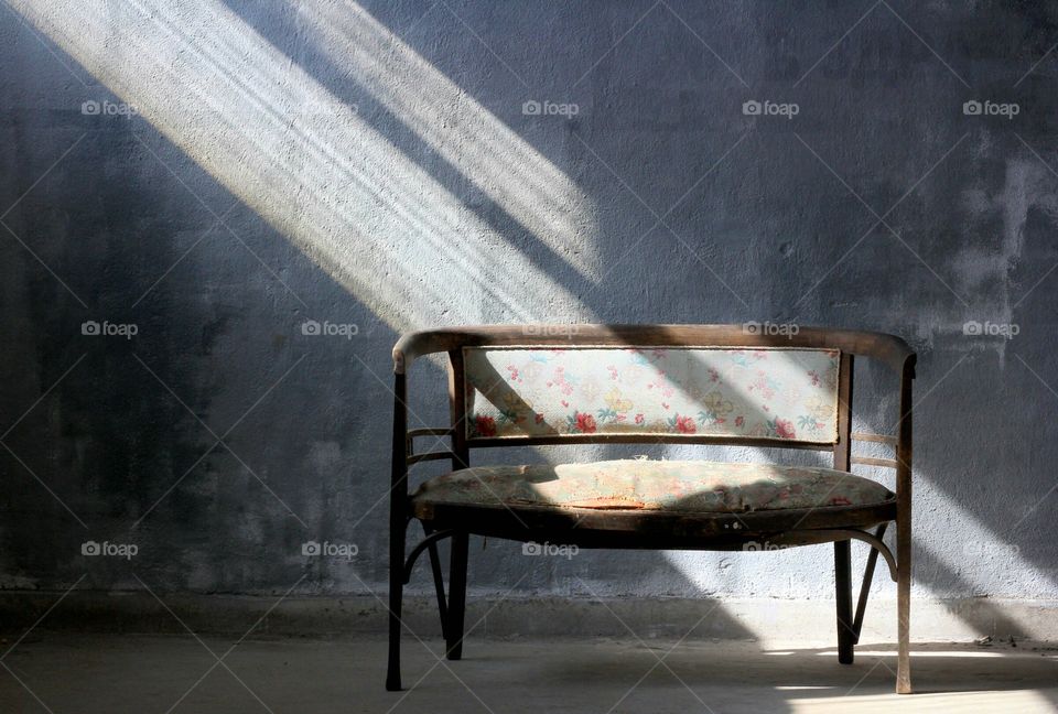 Empty bench indoor, sunlight beams over it
