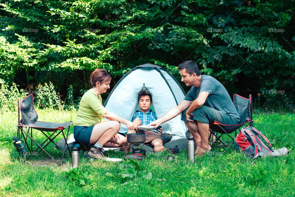 Spending a vacation on camping. Preparing a meal outdoor next to tent