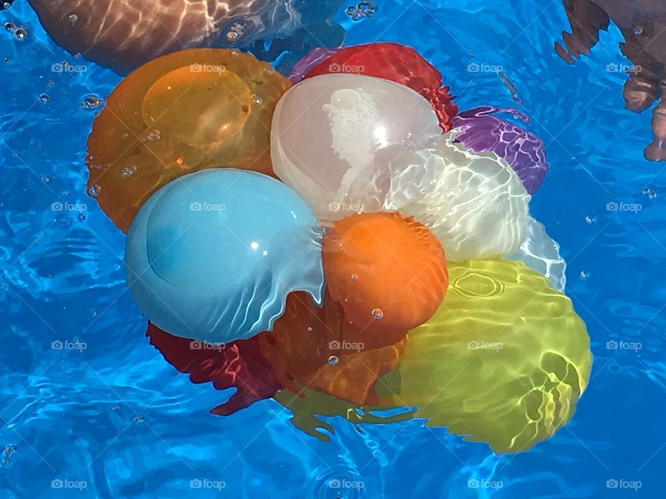 Water balloon bunch. Colourful group of water balloons floating. Swimming pool