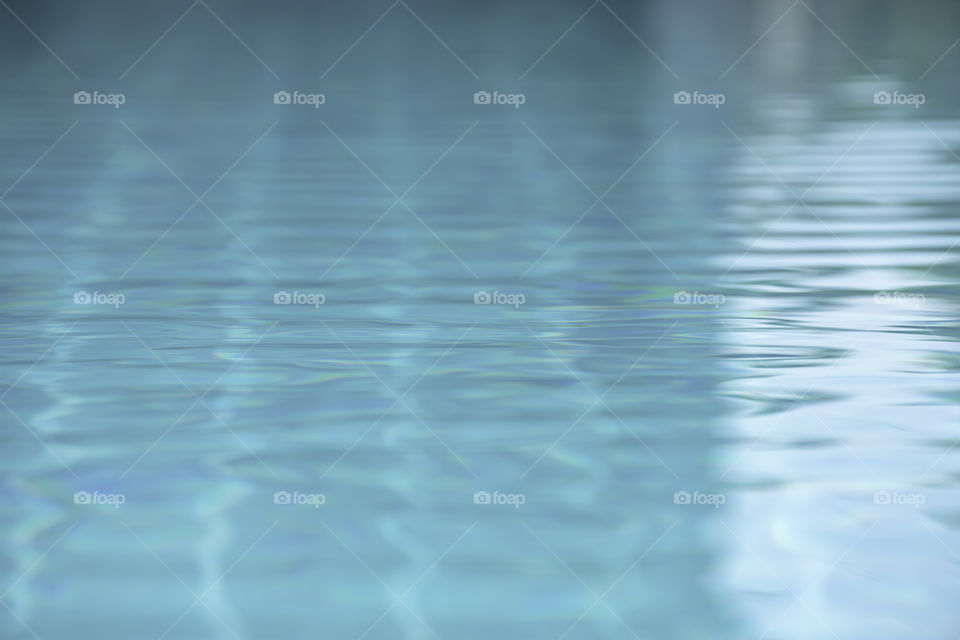 The blue water waves by wind and sunlight reflecting surface In the swimming pool.