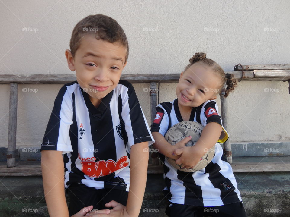 Brother and sister with a ball looking at camera and smiling