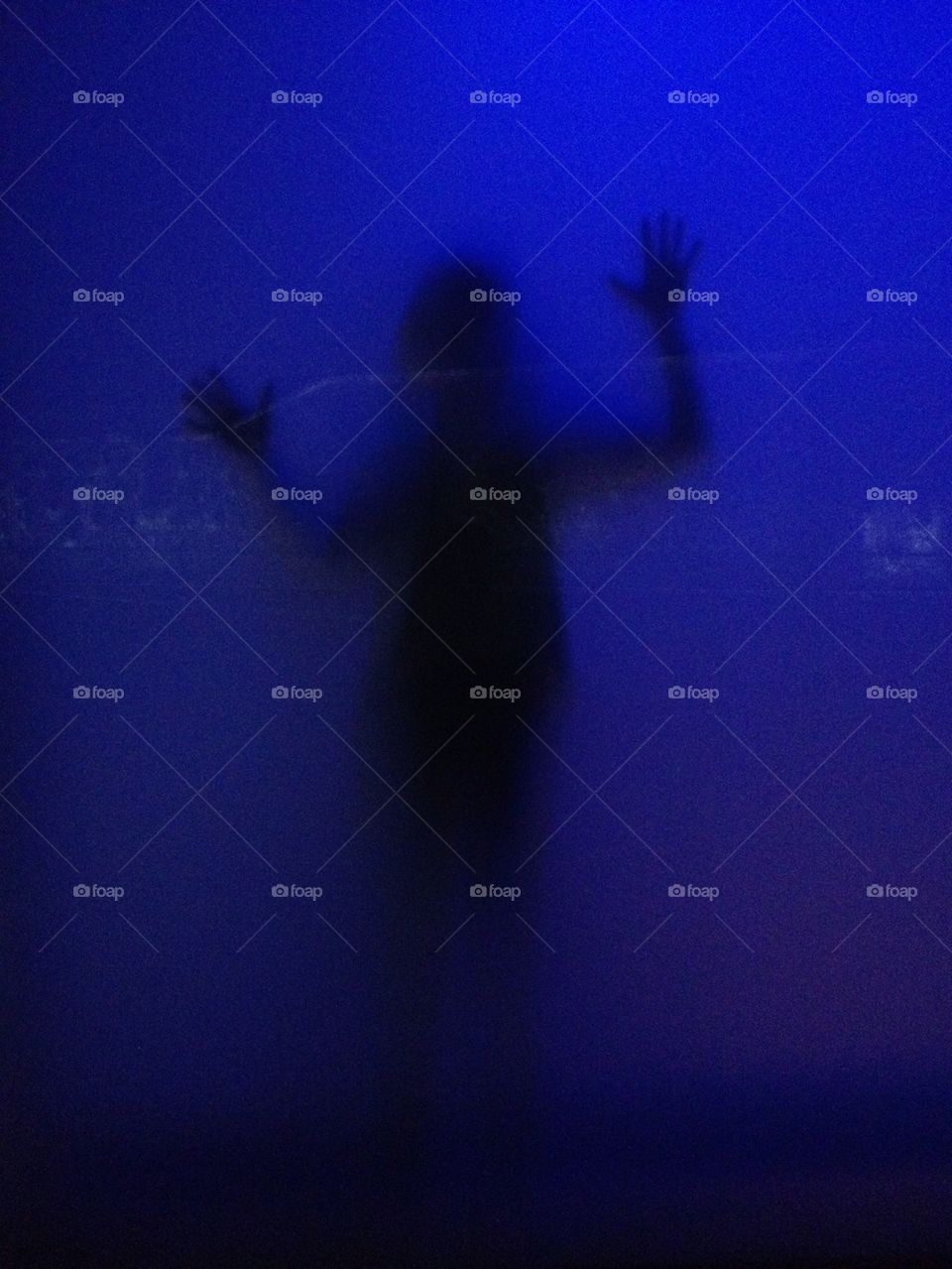 Silhouettes inside a glass cube with blue light.