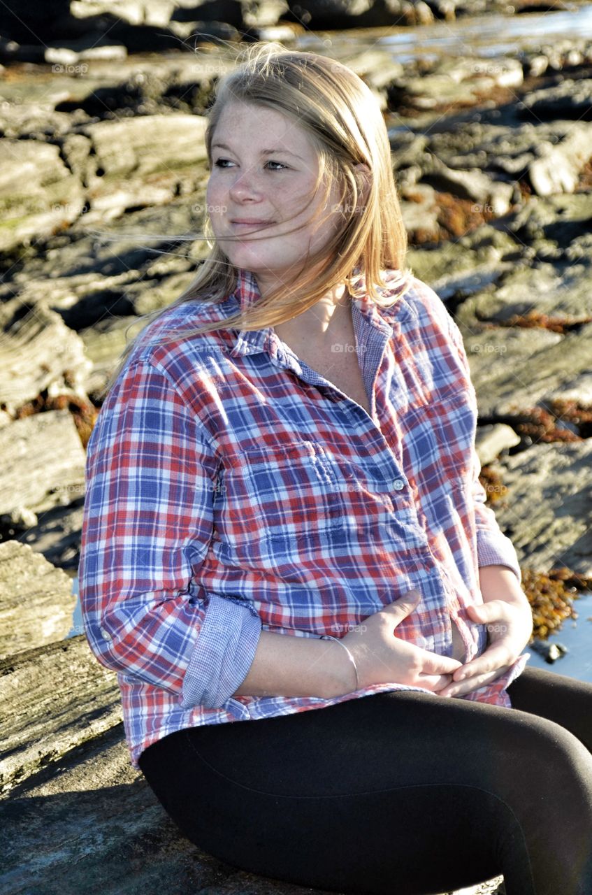 Beautiful young woman sitting on rock