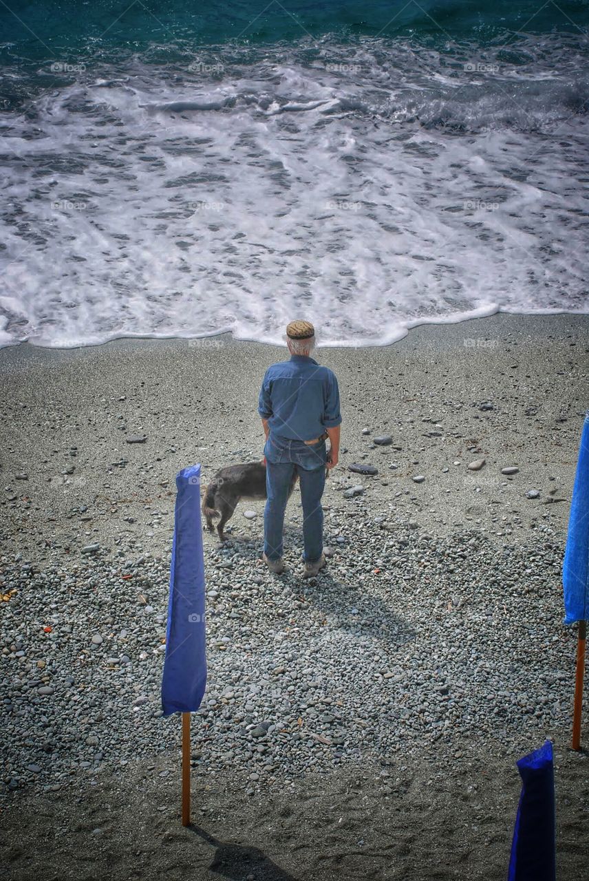 Lost in thought at the seaside. A man looks out to sea with his dog