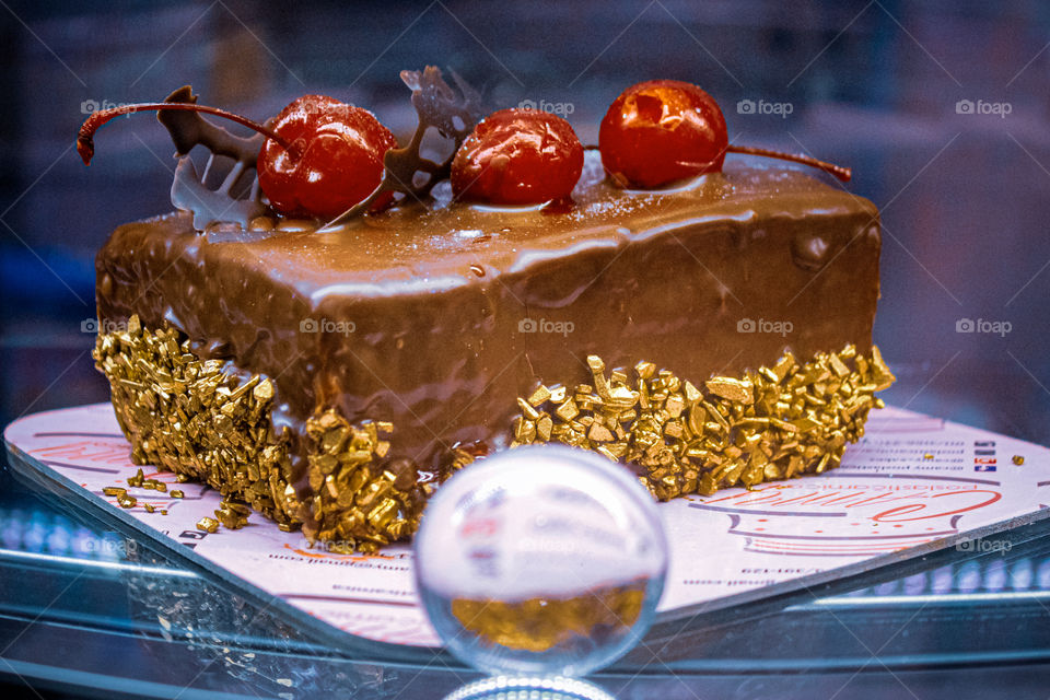 Chocolate cakes with three cherry, gold edition at chocolate cover, and crystal sphere ball at the bottom of the picture