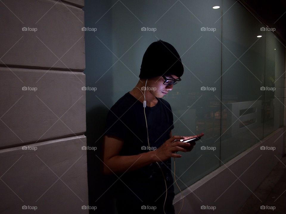 a teenager using a smartphone in a dark hallway